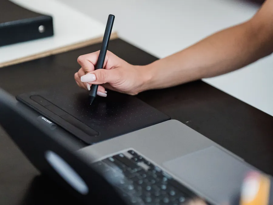 Designer using a graphic tablet beside a laptop