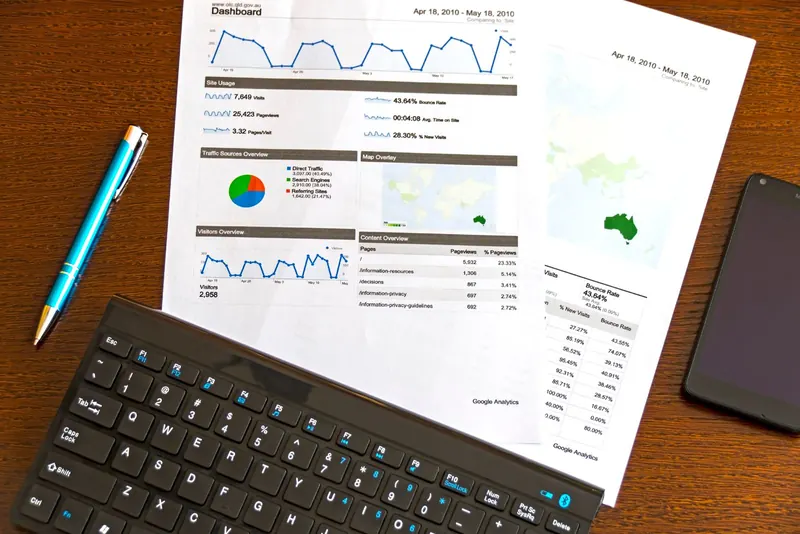 Printed analytics report, keyboard and phone on a desk