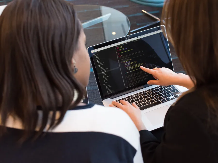 Two people reviewing code on a laptop during web development